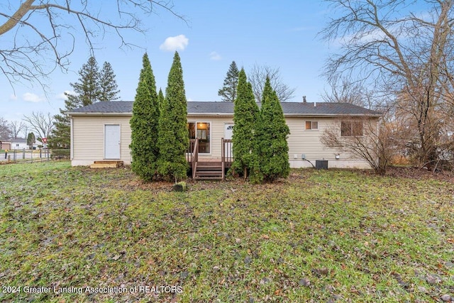 back of property featuring a lawn, a wooden deck, and central AC