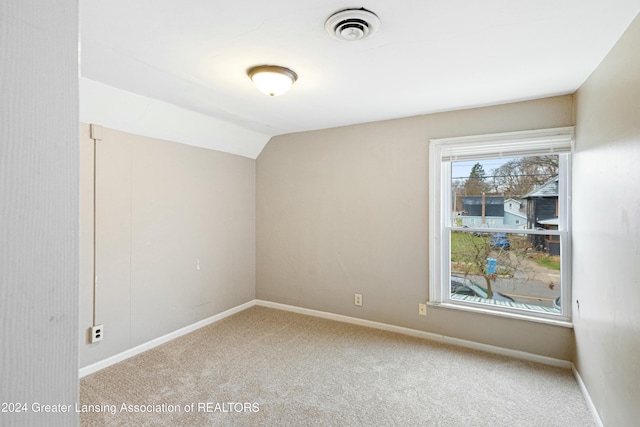 empty room with light carpet and vaulted ceiling