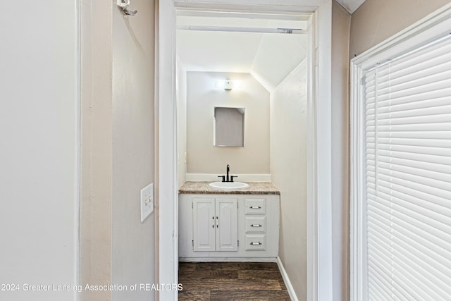 bathroom featuring vanity, wood-type flooring, and vaulted ceiling