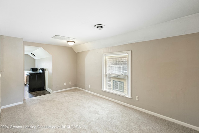 carpeted empty room featuring lofted ceiling