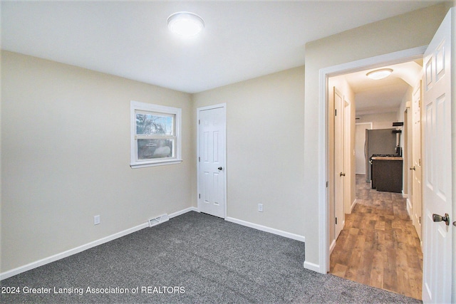 unfurnished bedroom with dark hardwood / wood-style flooring and a closet