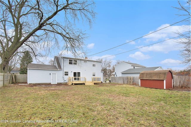 rear view of property featuring a yard, a deck, and a storage unit