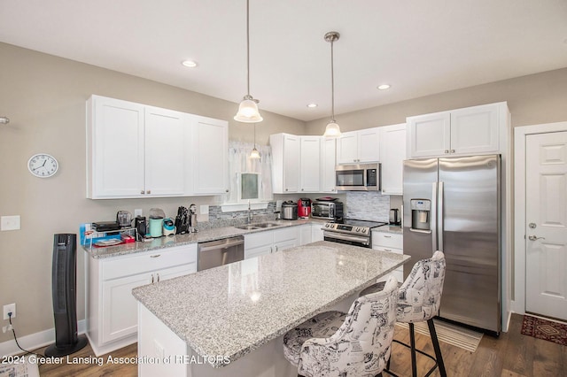 kitchen featuring sink, a center island, dark wood-type flooring, stainless steel appliances, and decorative light fixtures