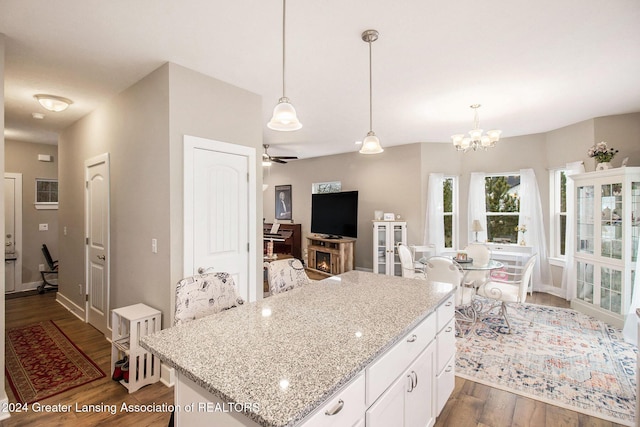 kitchen featuring light stone countertops, ceiling fan with notable chandelier, dark hardwood / wood-style floors, white cabinetry, and hanging light fixtures