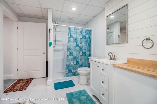 bathroom with a drop ceiling, walk in shower, vanity, tile patterned flooring, and toilet