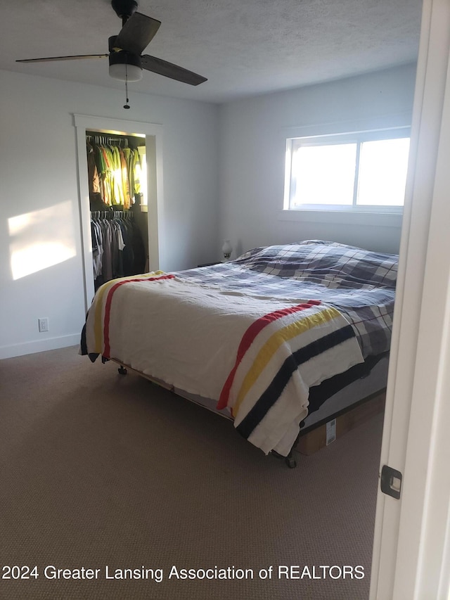 bedroom with ceiling fan, a closet, carpet floors, and a textured ceiling