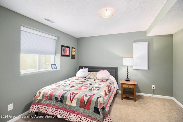 bedroom with light colored carpet and a textured ceiling