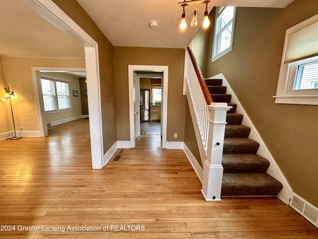 staircase with hardwood / wood-style flooring and a healthy amount of sunlight