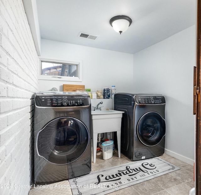 clothes washing area featuring washer and dryer and light tile patterned flooring