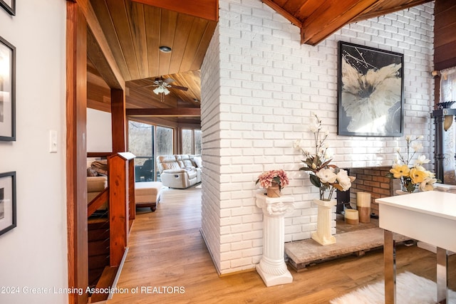 hallway featuring vaulted ceiling with beams, light wood-type flooring, wooden ceiling, and brick wall