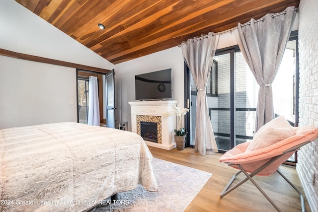 bedroom featuring lofted ceiling, access to outside, light wood-type flooring, wood ceiling, and a tiled fireplace