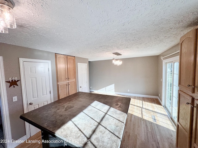 interior space featuring a chandelier, a textured ceiling, and light wood-type flooring