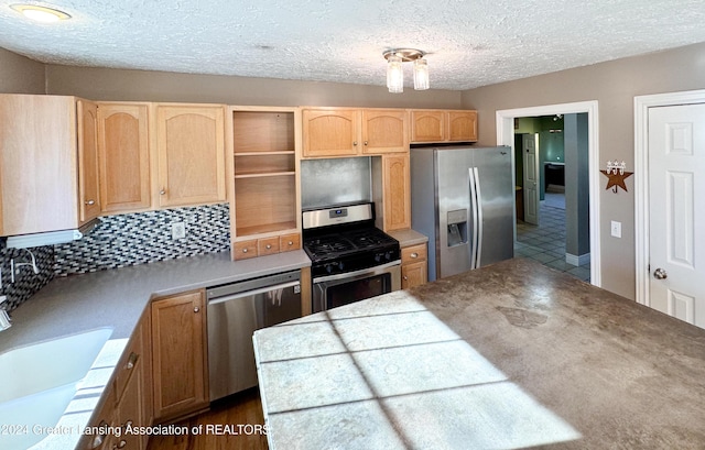 kitchen with decorative backsplash, stainless steel appliances, sink, light brown cabinets, and tile counters