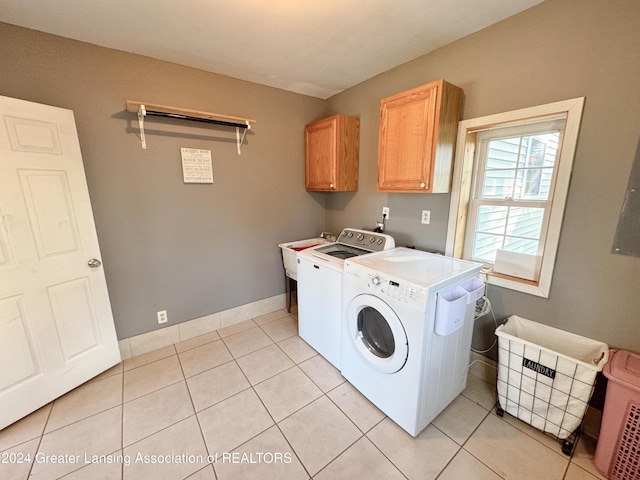 clothes washing area featuring cabinets, washer and clothes dryer, and light tile patterned flooring