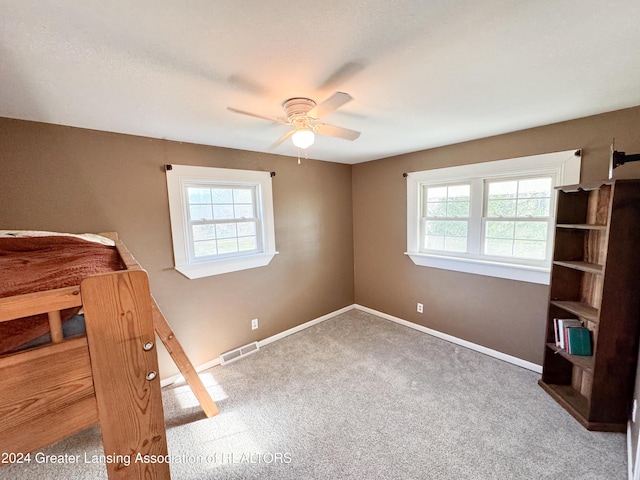 unfurnished bedroom with carpet, multiple windows, and ceiling fan