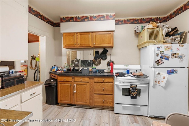 kitchen featuring sink, light hardwood / wood-style floors, and white appliances