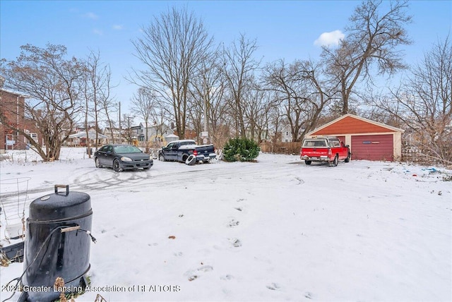 yard layered in snow featuring an outbuilding and a garage