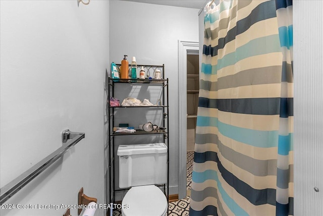 bathroom with a shower with shower curtain and toilet