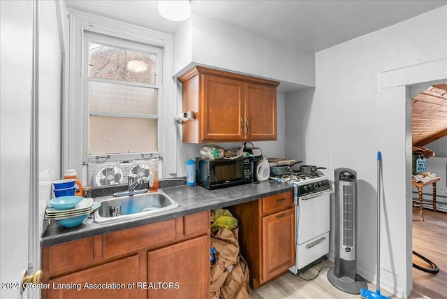 kitchen with gas range gas stove, sink, and light wood-type flooring