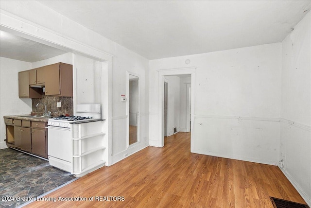 kitchen featuring sink, backsplash, white gas range oven, and hardwood / wood-style floors