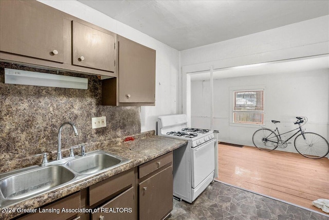 kitchen featuring sink, white range with gas cooktop, and backsplash