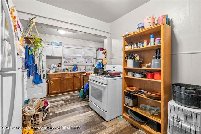 kitchen with white range with gas cooktop, white cabinets, and hardwood / wood-style flooring