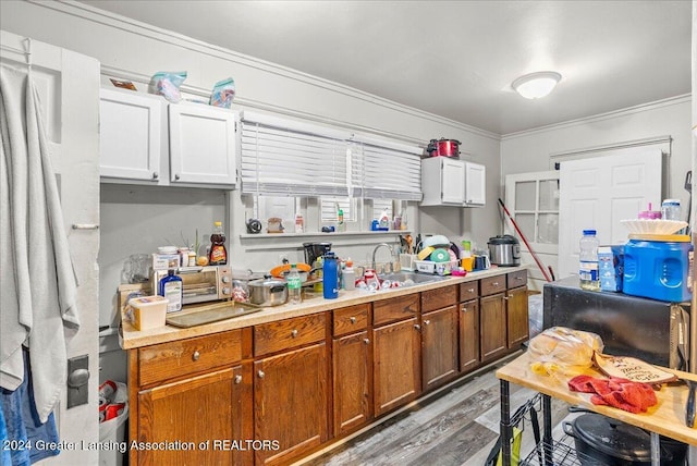 kitchen featuring sink, light hardwood / wood-style floors, white cabinetry, and ornamental molding