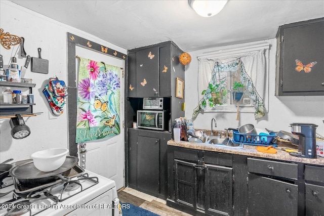 kitchen featuring sink, white range with gas cooktop, and light hardwood / wood-style flooring