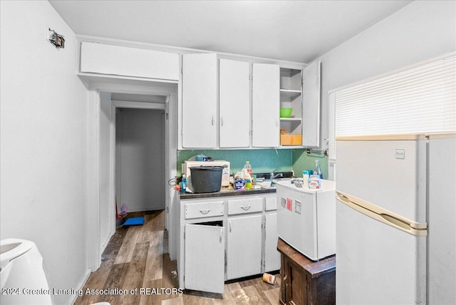 kitchen with white cabinetry, white refrigerator, and light hardwood / wood-style flooring