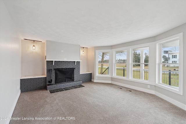 unfurnished living room featuring light carpet and a brick fireplace