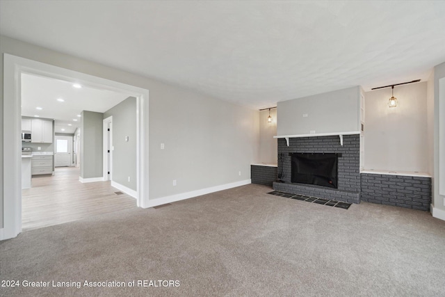 unfurnished living room featuring light carpet and a brick fireplace