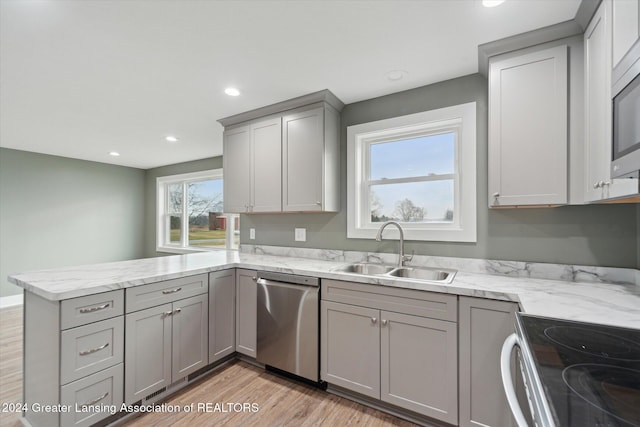 kitchen with sink, stainless steel dishwasher, kitchen peninsula, gray cabinets, and light wood-type flooring