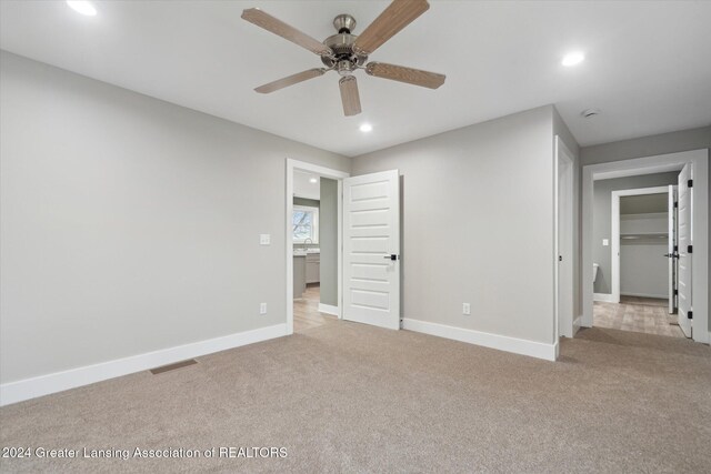 unfurnished bedroom featuring ceiling fan, light carpet, and a closet