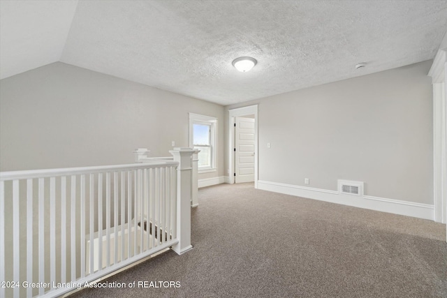 unfurnished room with a textured ceiling, carpet floors, and vaulted ceiling