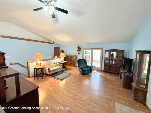 living room featuring a textured ceiling, light hardwood / wood-style floors, vaulted ceiling, and ceiling fan