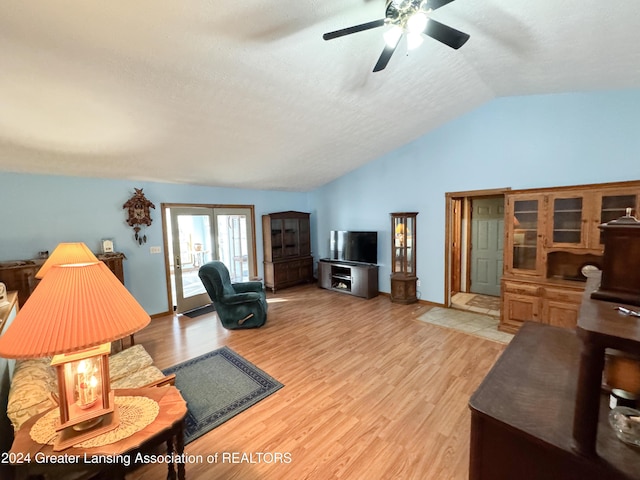 living room featuring hardwood / wood-style flooring, ceiling fan, lofted ceiling, and a textured ceiling