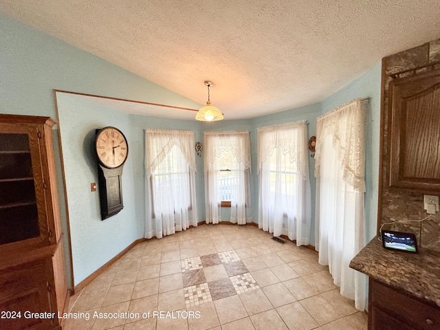 unfurnished dining area featuring lofted ceiling, light tile patterned floors, and a textured ceiling