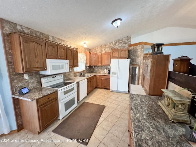 kitchen with sink, vaulted ceiling, a textured ceiling, white appliances, and light tile patterned floors