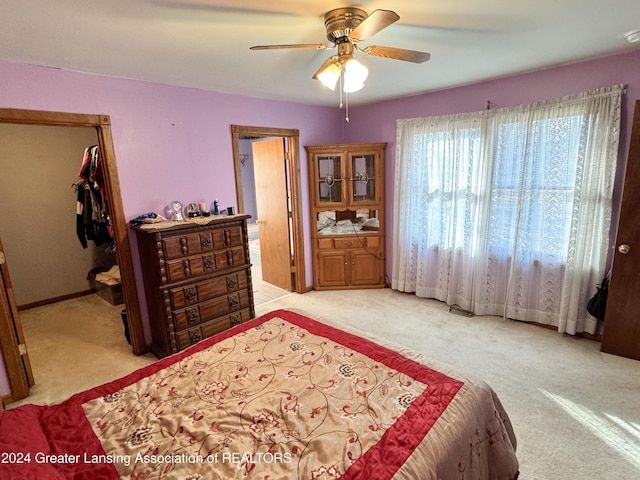 carpeted bedroom with a closet, ensuite bath, and ceiling fan