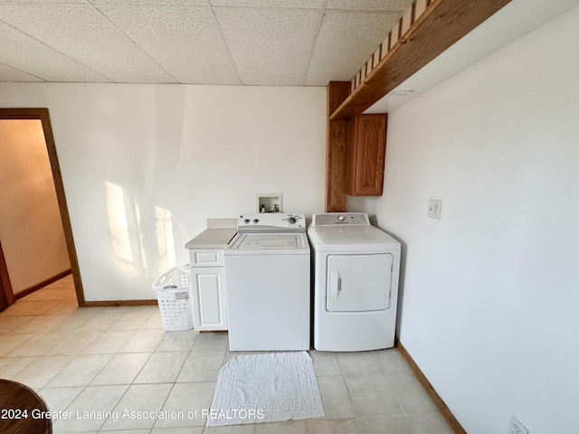 laundry room featuring cabinets, light tile patterned floors, and washer and clothes dryer