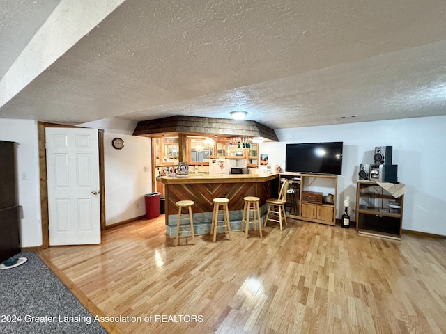 bar featuring a textured ceiling and light wood-type flooring