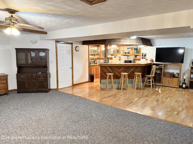 interior space featuring ceiling fan, beamed ceiling, white fridge, a textured ceiling, and light wood-type flooring