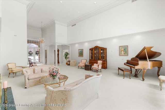 carpeted living room featuring ornate columns, a towering ceiling, ornamental molding, and french doors