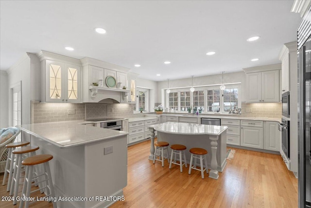 kitchen with a breakfast bar, white cabinets, light hardwood / wood-style flooring, appliances with stainless steel finishes, and a kitchen island