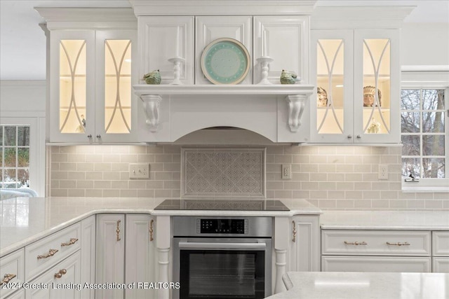 kitchen featuring white cabinets, stainless steel oven, and tasteful backsplash