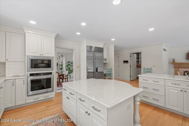 kitchen featuring crown molding, built in appliances, light hardwood / wood-style flooring, white cabinets, and a kitchen island