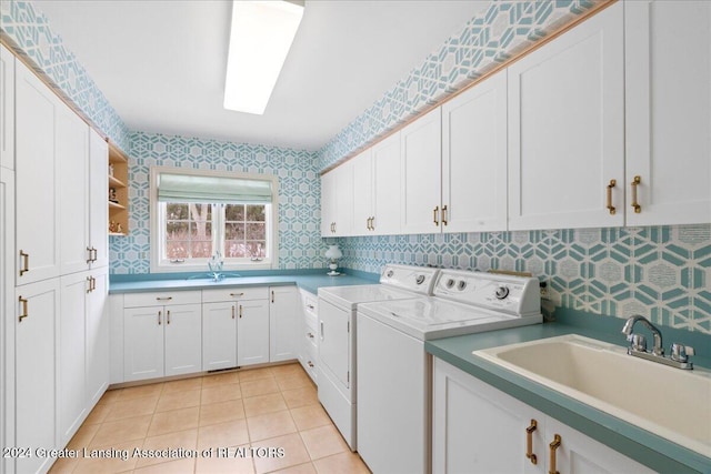 laundry room with light tile patterned flooring, cabinets, sink, and washing machine and clothes dryer