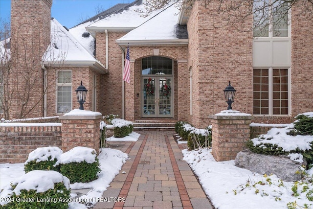 snow covered property entrance featuring french doors