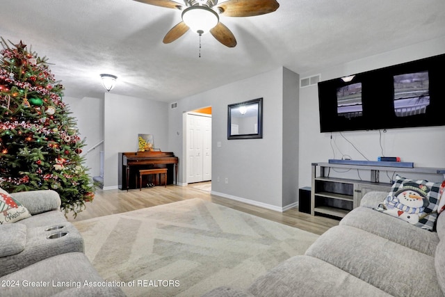 living room featuring ceiling fan, a textured ceiling, and light wood-type flooring