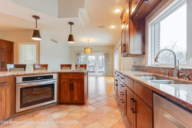 kitchen featuring sink, decorative light fixtures, a healthy amount of sunlight, and appliances with stainless steel finishes